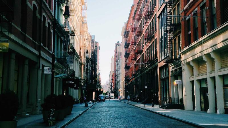 A man drinking coffee and reading a supplement bottle at a desk